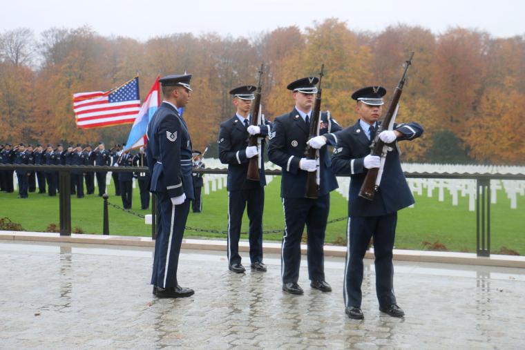 Men in uniform stand with firearm. 