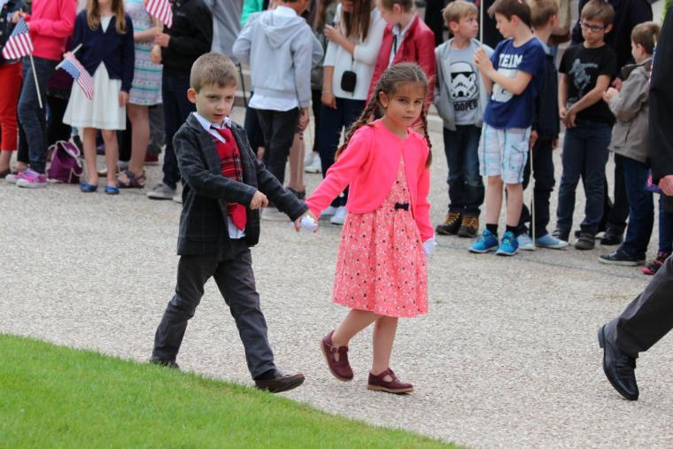 A boy and a girl hold hands during the ceremony. 