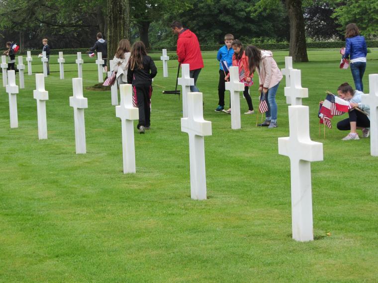 Students place American and French flags at the headstones.
