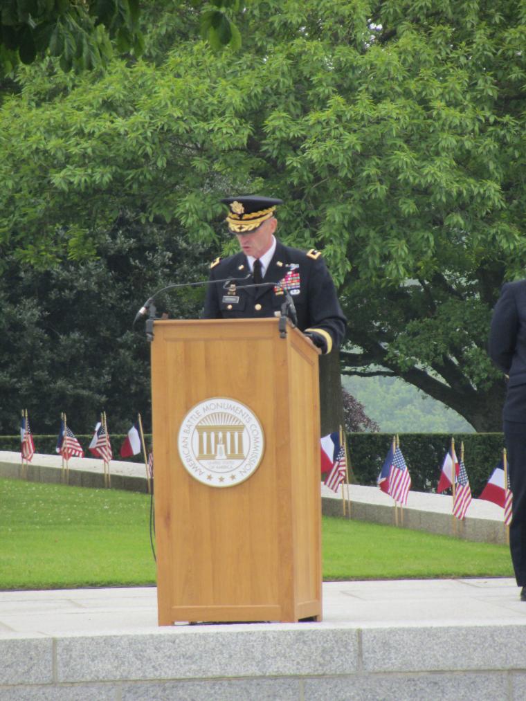 Maj. Gen. stands at a podium delivering his remarks.