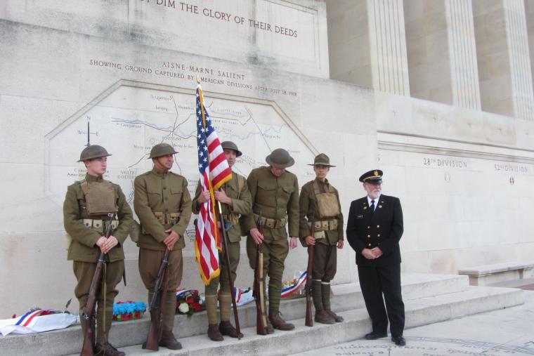 Men in World War I uniforms stand with cemetery superintendent. 