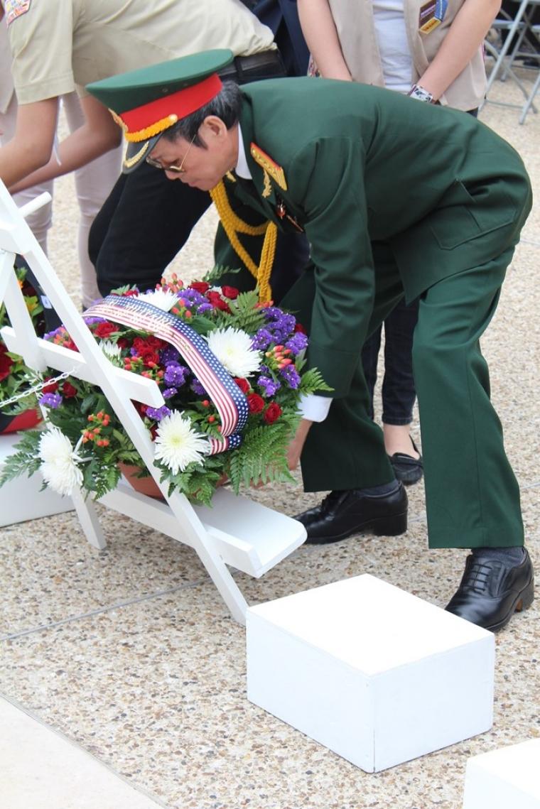 Man in uniform lays a floral wreath.