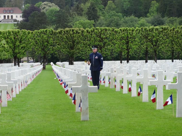 A member of the American military plays the bugle amidst the headstones. 