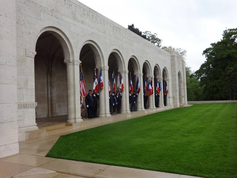 Men with flags stand under the stone archways outside the chapel. 