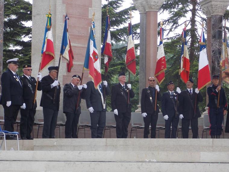 Men in suits stand with flags during the ceremony.