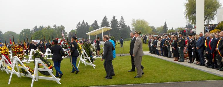 WWII veterans are escorted by cemetery staff as they prepare to lay a wreath.