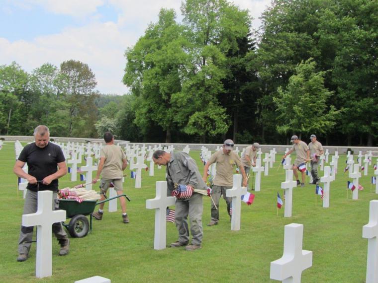 Members of the grounds' crew place flags in front of every headstone.