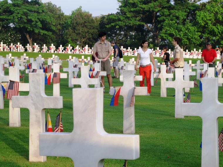 Volunteers place American and Filipino flags in the ground. 