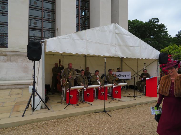 Members of a band sit under a tent, and play. 
