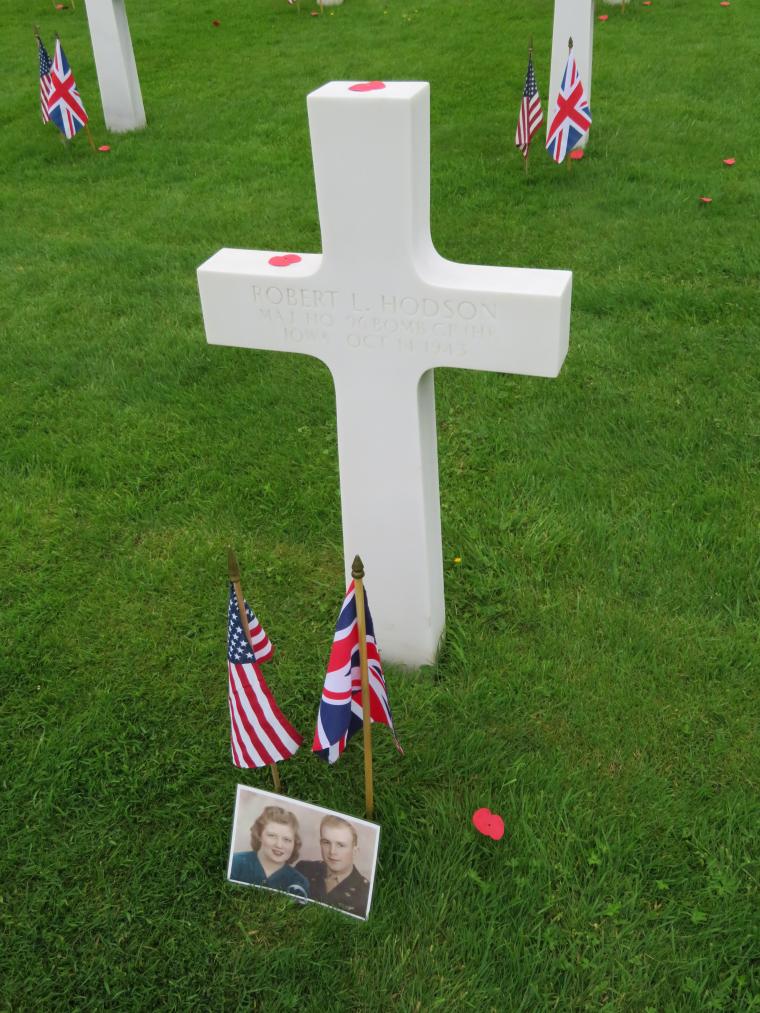 A photo, along with an American and British flag, are in front of a headstone.