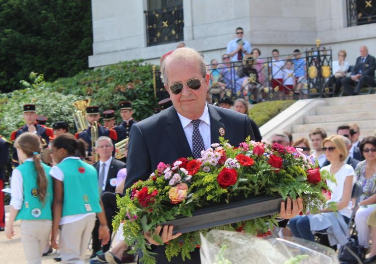 Man in a suit prepares to lay a wreath. 