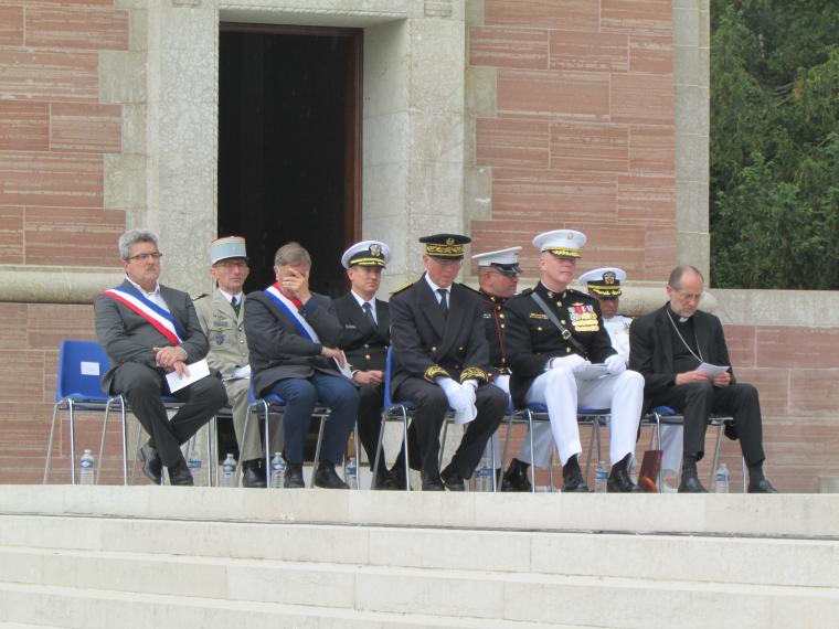 Men in suits and uniforms sit in chairs. 