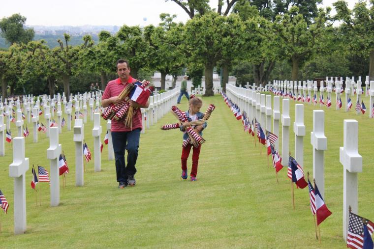 A man and a girl help with the American and French flags.