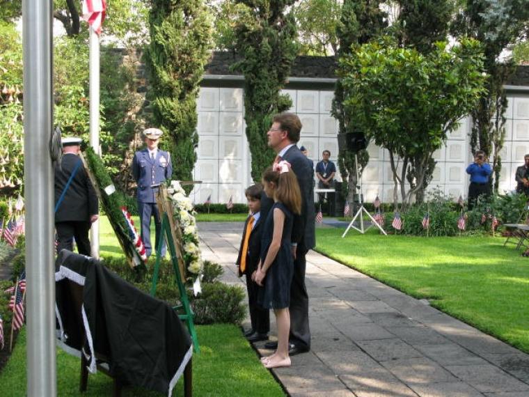 A man and two children lay a wreath. 