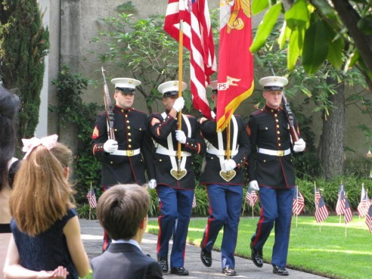 Marines in uniform march with the flags and rifles.