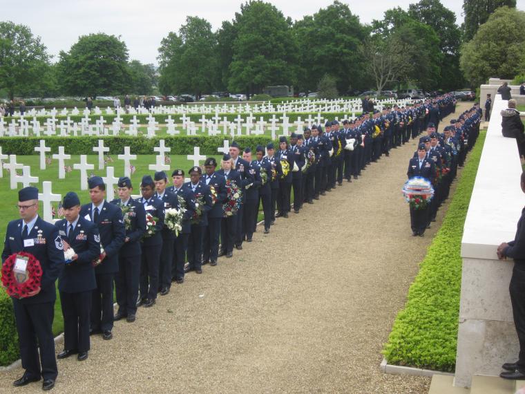 Members of the Air Force stand in line with floral wreaths. 