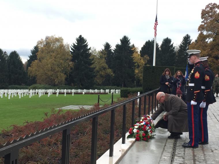 Thomas Lamont bends down to place a wreath. 