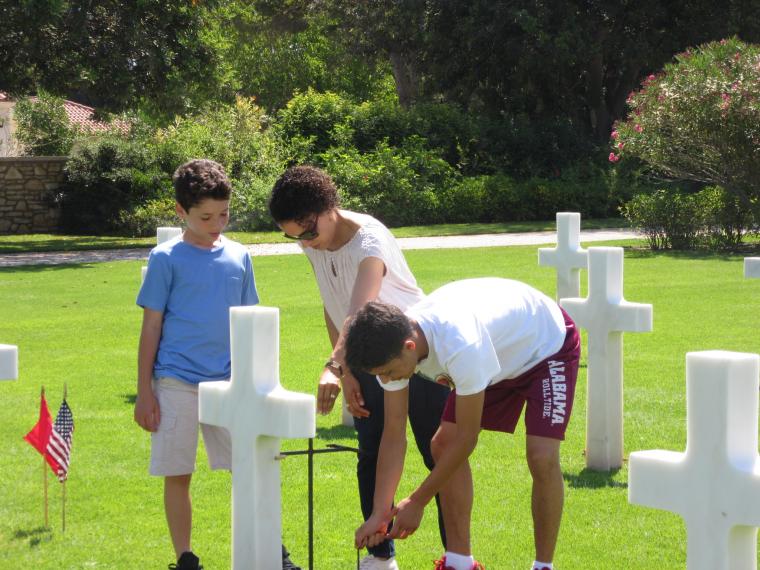 A woman and two boys help place the flags. 