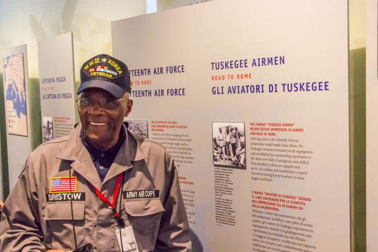 Bristow stands next to a panel about the Tuskegee Airmen. 