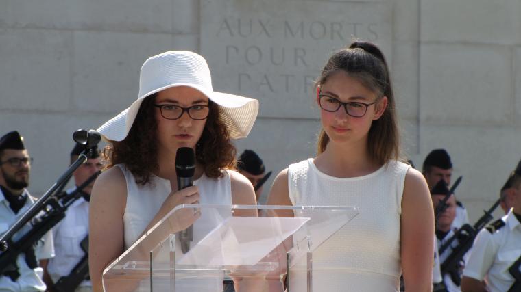 Two girls, dressed in white, stand at the podium to read the poetry.