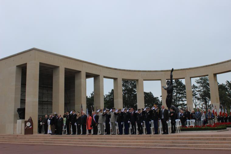 Men and women stand in the memorial area during the ceremony. 