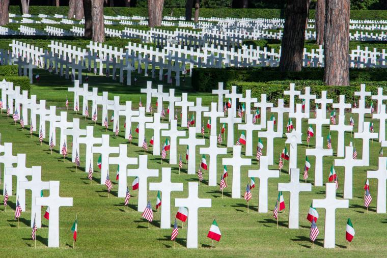 Rows of headstones with American and Italian flags cover the landscape. 