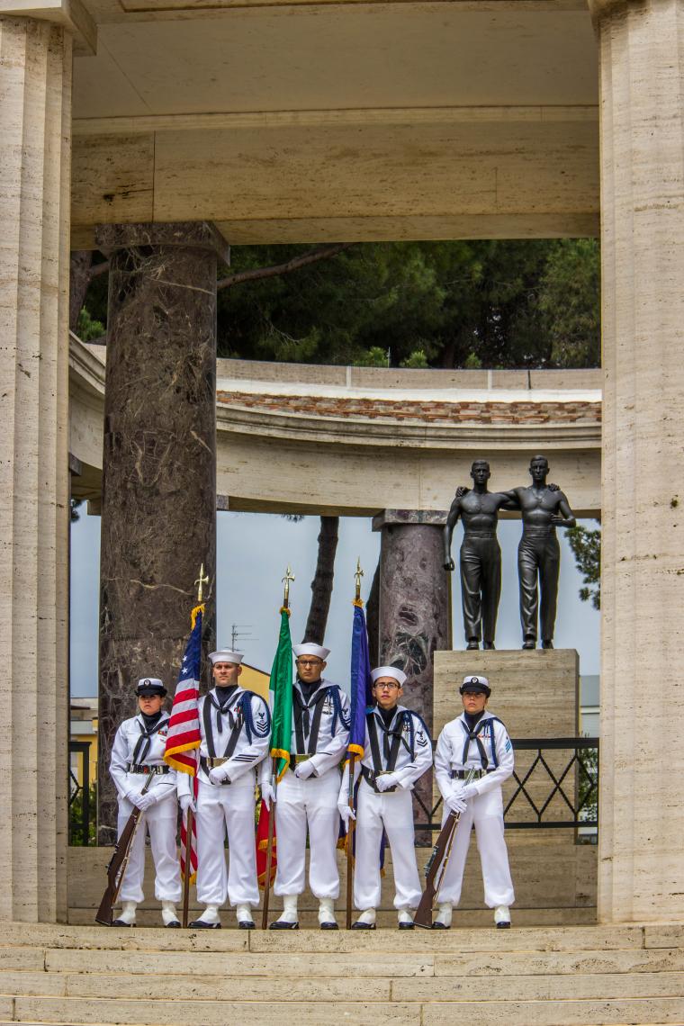 An Honor Guard in uniform stands in front of the Brothers in Arms statue. 