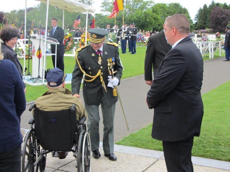 Man in uniform shakes hands with veteran. 