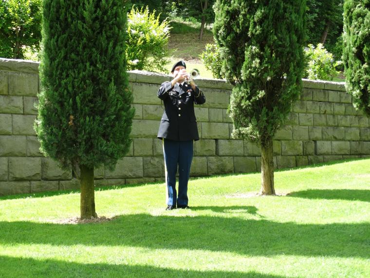 A man in uniform plays the trumpet in the plot area during the ceremony.