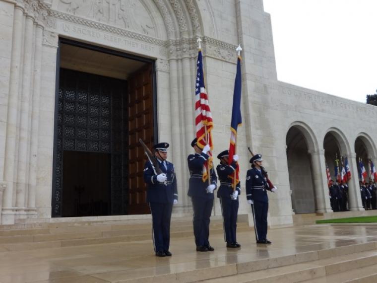 A U.S. Color Guard stands with flags and rifles outside the chapel. 