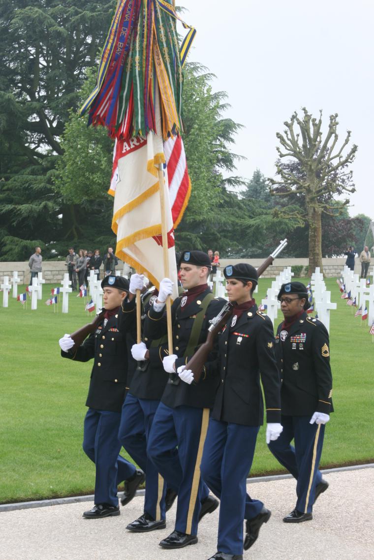 An American honor guard marches with flags and rifles.
