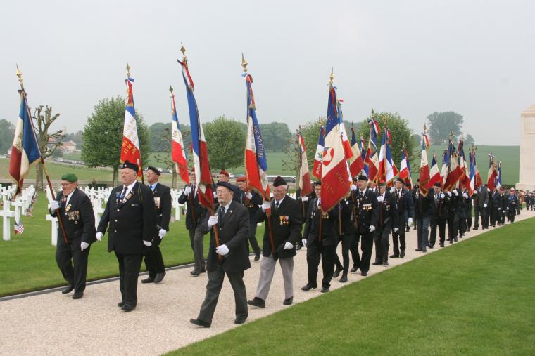 Men in suits carry flags during the ceremony. 
