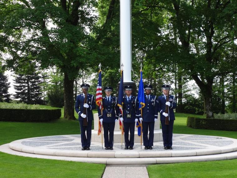 A U.S. Honor Guard stands in the ready position at the base of the flag pole. 