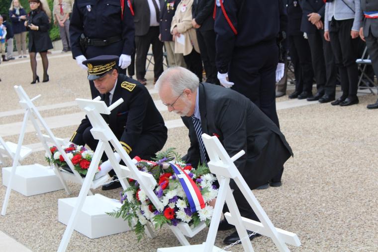 Two men kneel down to lay wreaths during the ceremony. 