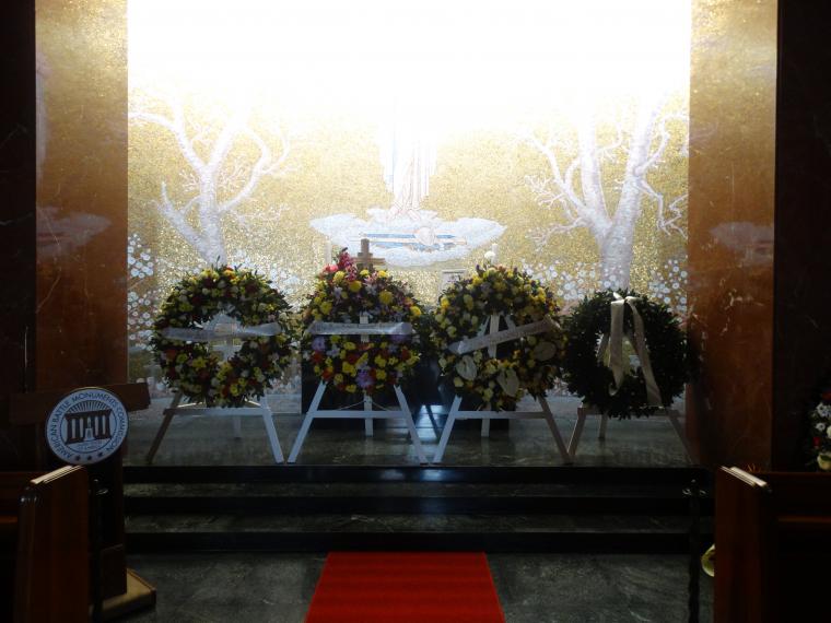 Four floral wreaths rest on stands in the chapel.
