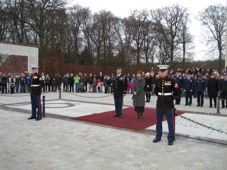 A woman and man in uniform stand next to each other, ready to lay a wreath. 