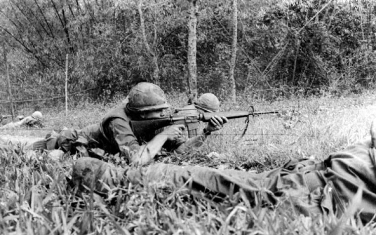 Historic photo shows a man firing a weapon. 