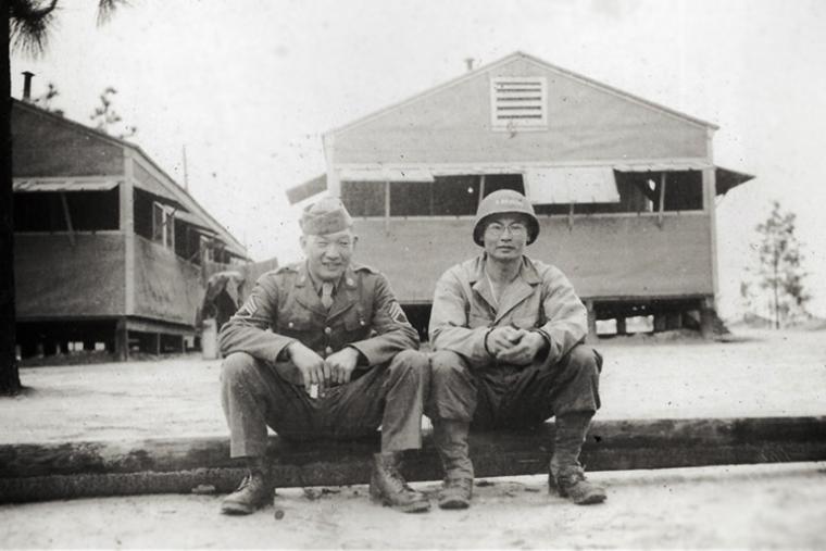 Historic image showing Victor and Johnny in uniform sitting on curb. 